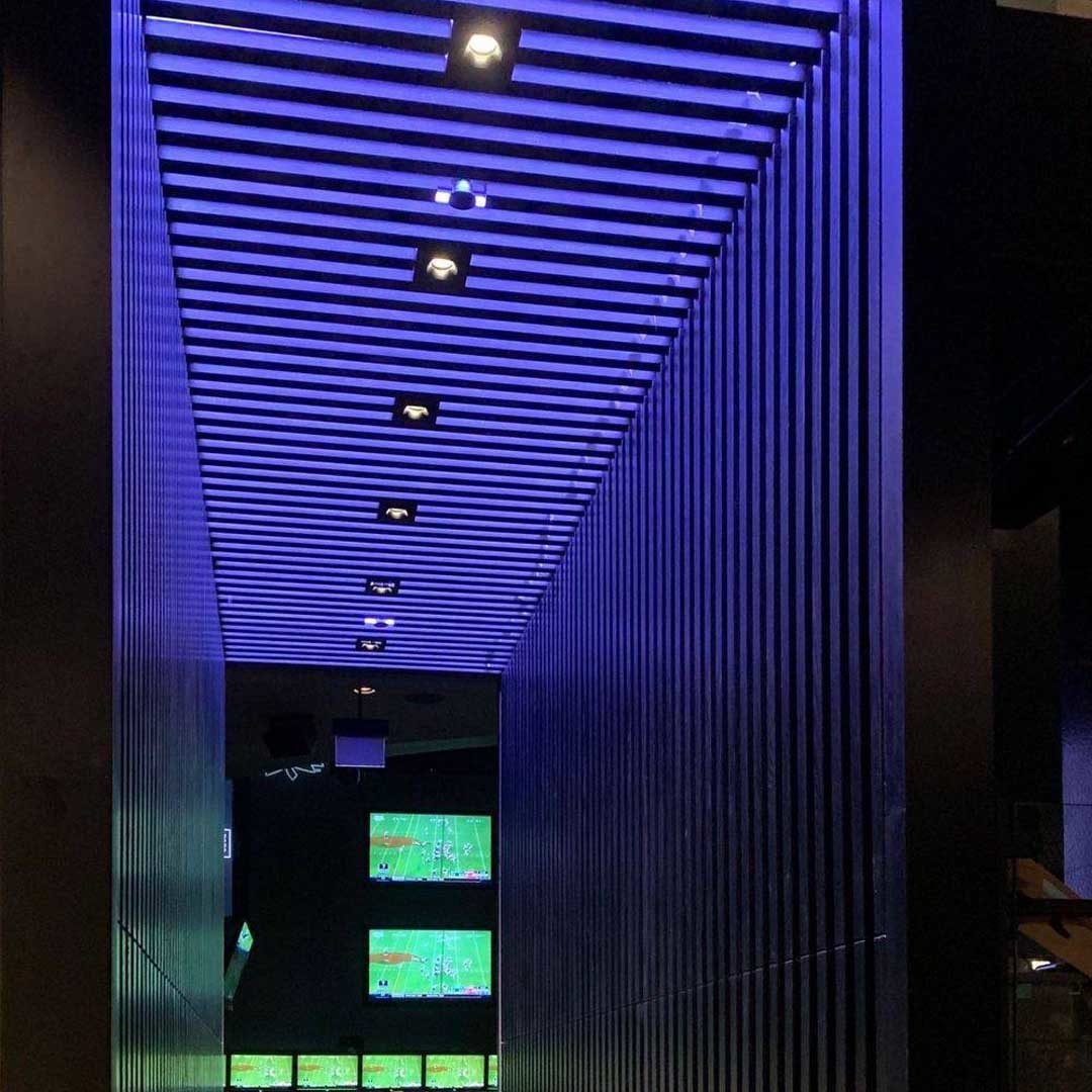Photograph of a hallway decorated with wood and neon lights.